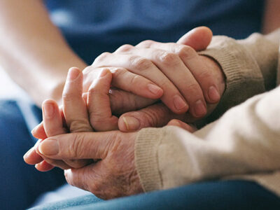 close up of two people holding hands in comfort