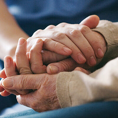 close up of two people holding hands in comfort