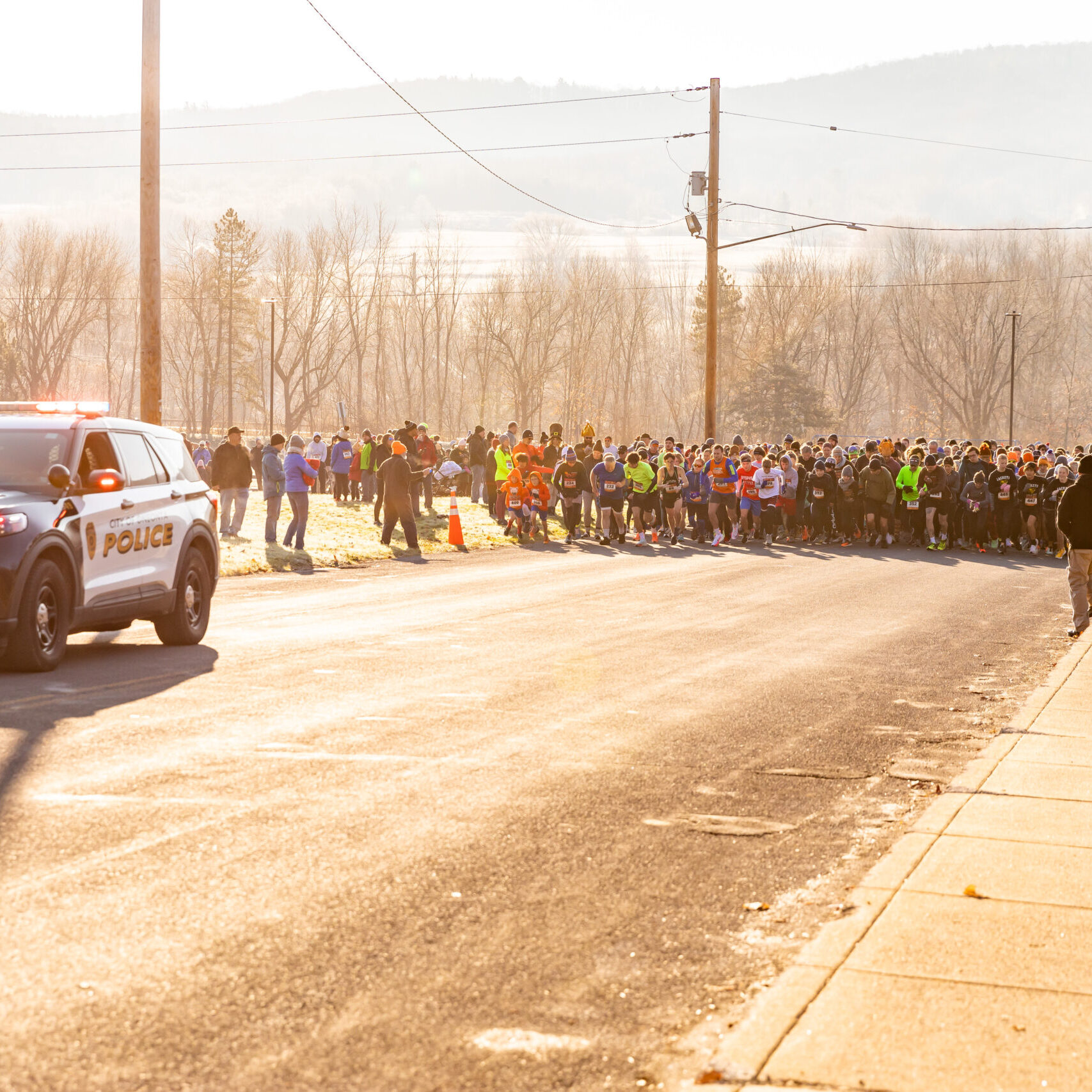Runners waiting to begin a race behind a police car