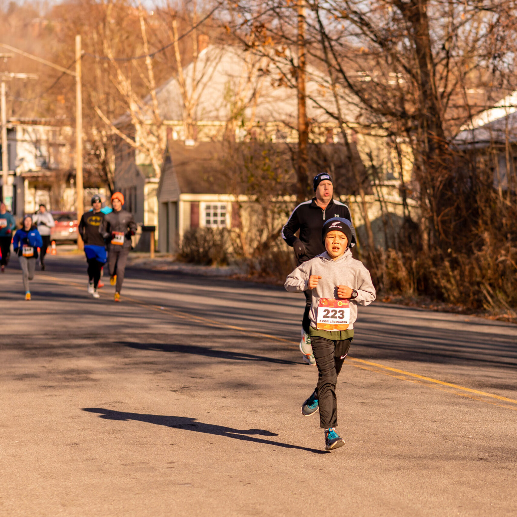 Little boy running ahead of other runners