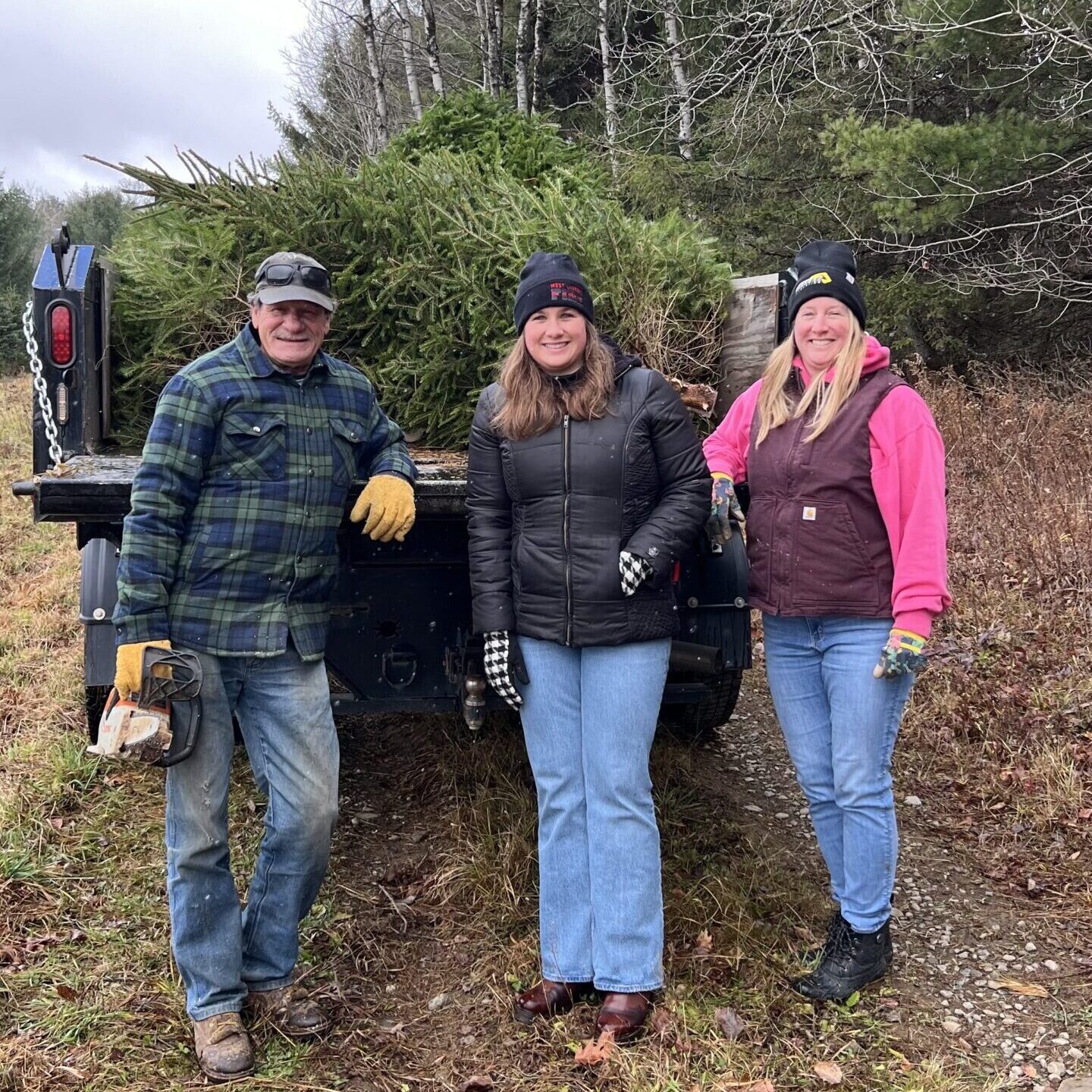 Three people standing in front of trees