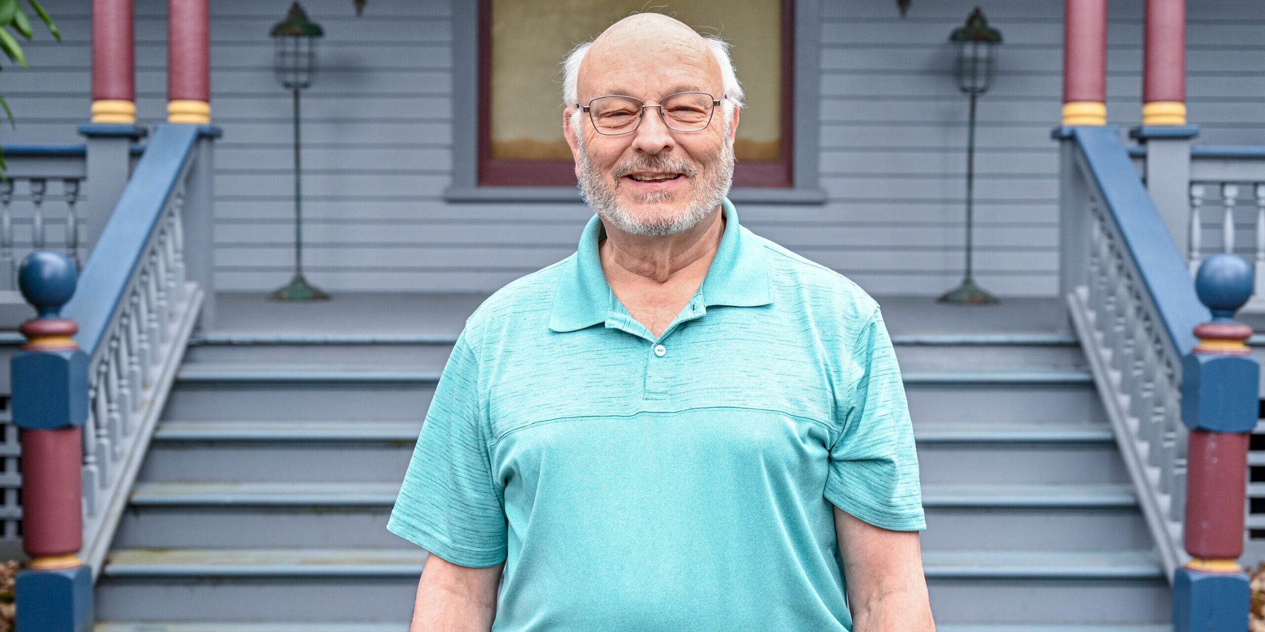Man smiling and standing in front of blue house