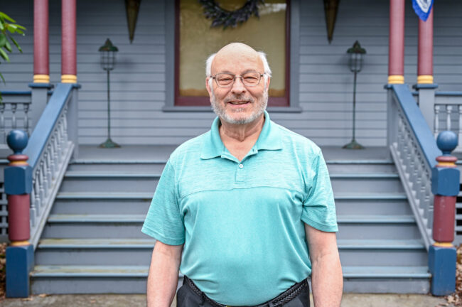 Z6 Man smiling and standing in front of blue house