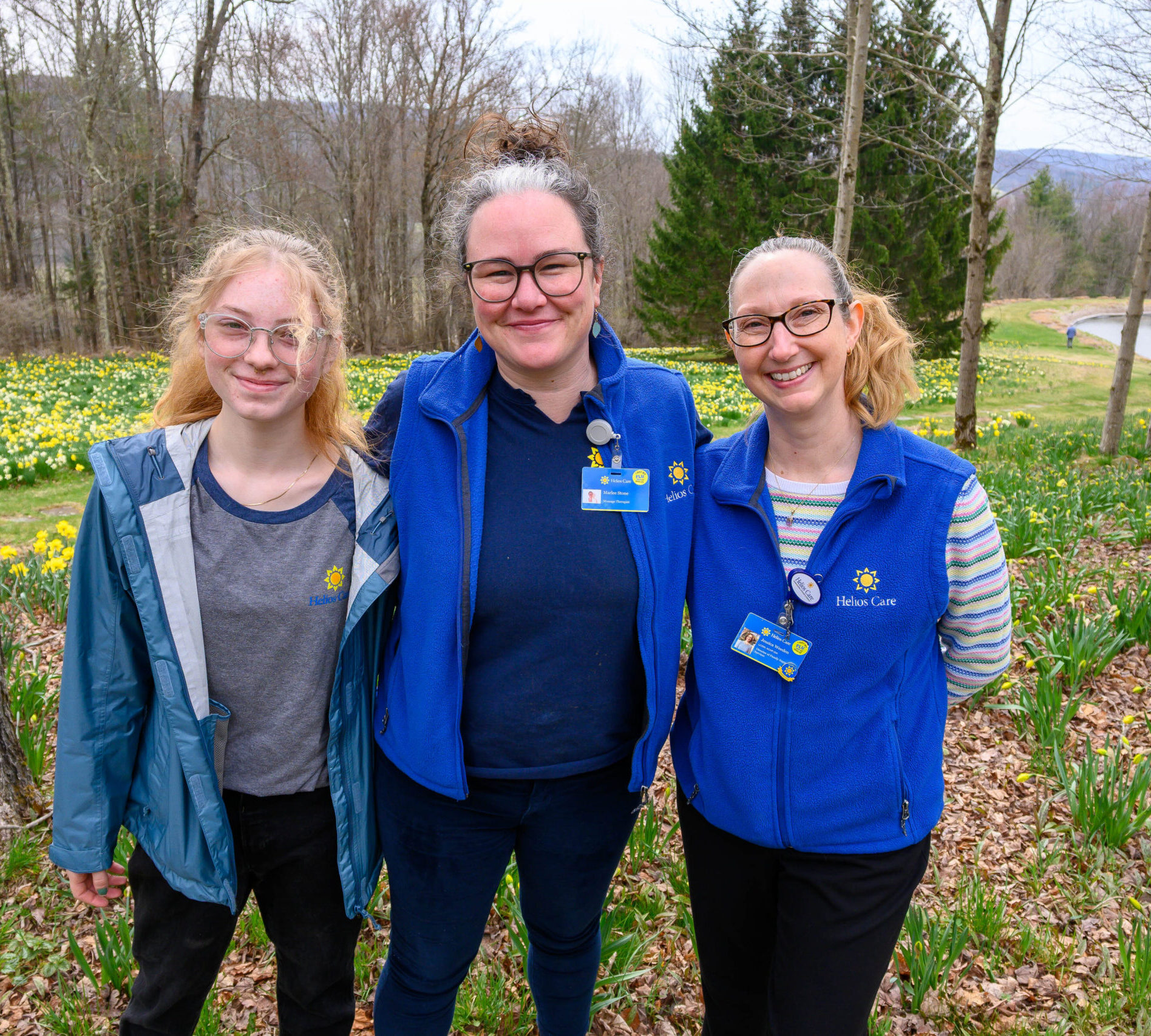 Three women standing in front of daffodils